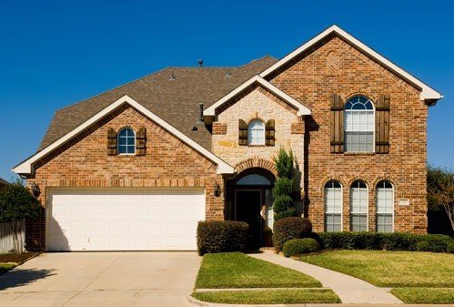 Before example showing a plain white double garage door on a brick home